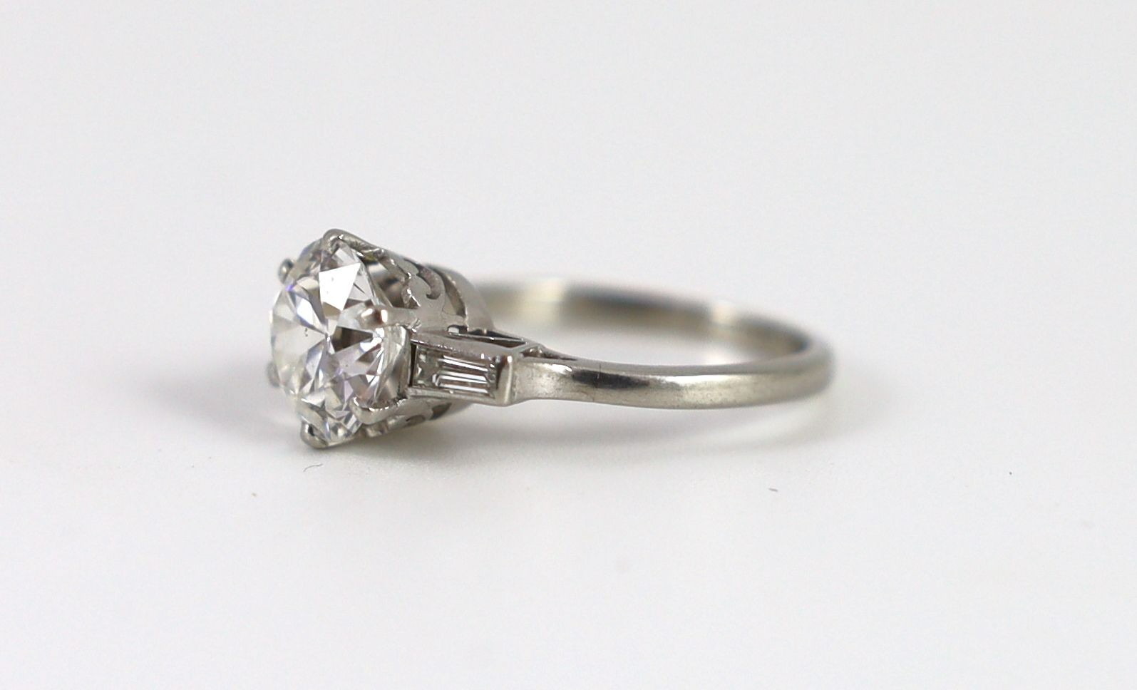 A mid 20th century platinum and single stone diamond ring, with trapeze cut diamond set shoulders
